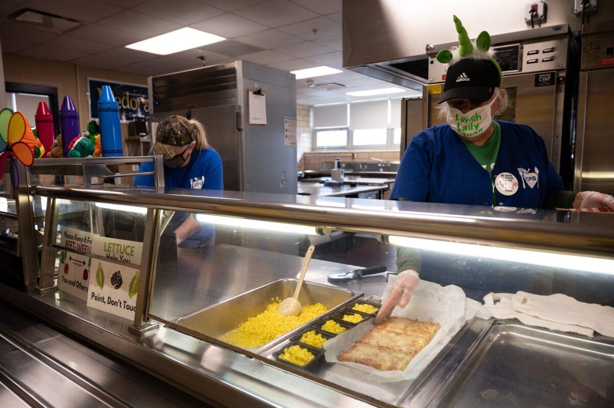 Masked cafeteria workers serve food during a socially distanced lunch at Medora Elementary School in Louisville, Ky., on March 17, 2021. (Jon Cherry/Getty Images)