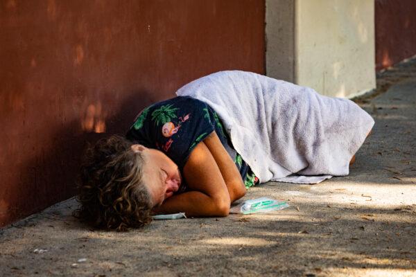 A homeless woman sleeps on the streets of Santa Ana, Calif., on Sept. 4, 2020. (John Fredricks/The Epoch Times)