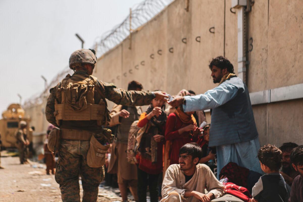 A U.S. Marine passes out water during the evacuation at Hamid Karzai International Airport in Kabul, Afghanistan, on Aug. 21, 2021. (U.S. Marine Corps/Isaiah Campbell/Getty Images)