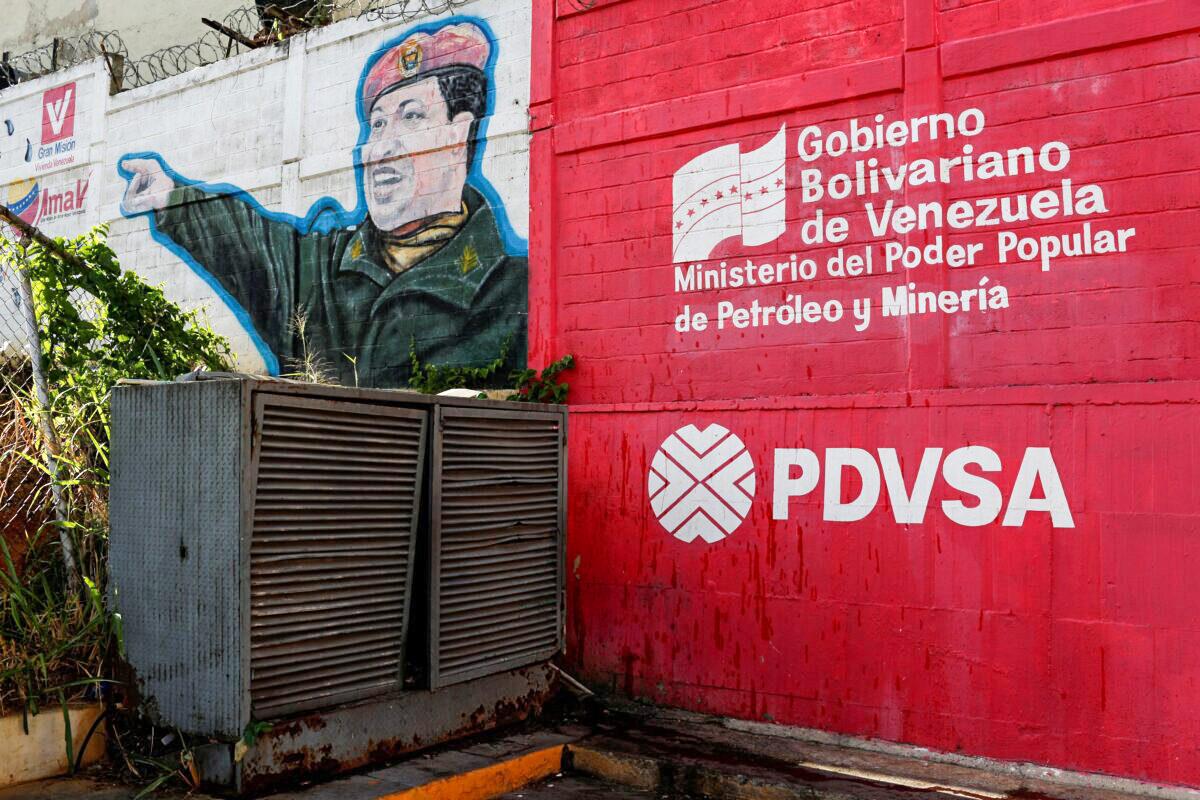 The logo of the Venezuelan state oil company PDVSA is seen next to a mural depicting Venezuela's late President Hugo Chavez at a gas station in Caracas, Venezuela, on March 2, 2017. (Carlos Garcia Rawlins/Reuters)
