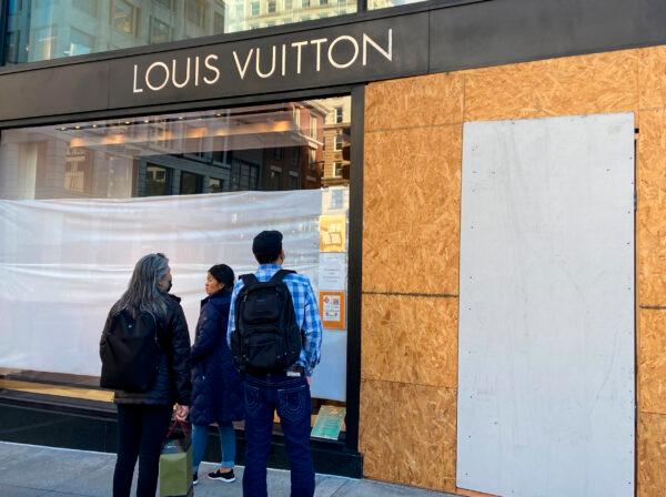 Union Square visitors look at damage to the Louis Vuitton store on Nov. 21, 2021, after looters ransacked businesses late Saturday night in San Francisco. (Danielle Echeverria/San Francisco Chronicle via AP)