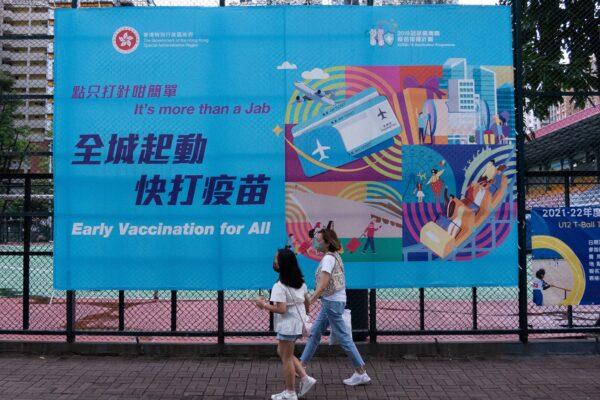 People walk past a government banner encouraging the public to take the Covid-19 vaccine in Hong Kong on Aug. 15, 2021. (Bertha Wang/AFP via Getty Images)