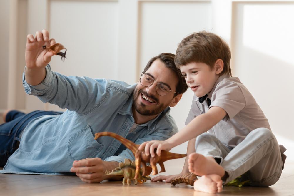 A boy plays with toy dinosaurs with his father in this file photo. (fizkes/Shutterstock)