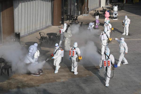 Staff members wearing personal protective equipment spray disinfectant outside a shopping mall in Xi'an, China, on Jan. 11, 2022. (STR/AFP via Getty Images)