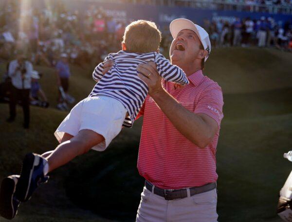 Hudson Swafford lifts his son James after winning the American Express golf tournament on the Pete Dye Stadium Course at PGA West in La Quinta, Calif., on Jan. 23, 2022. (Marcio Jose Sanchez/AP Photo)
