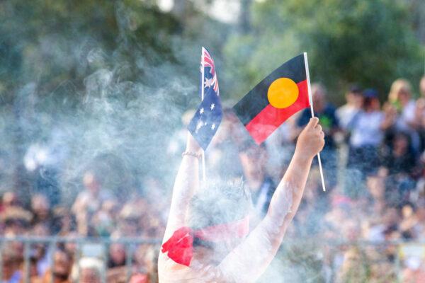 A member of the Koomurri dancers holds up an Indigenous and Australian flag during the WugulOra Morning Ceremony on Australia Day at Walumil Lawns, Barangaroo in Sydney, Australia, on Jan. 26, 2020. (Jenny Evans/Getty Images)