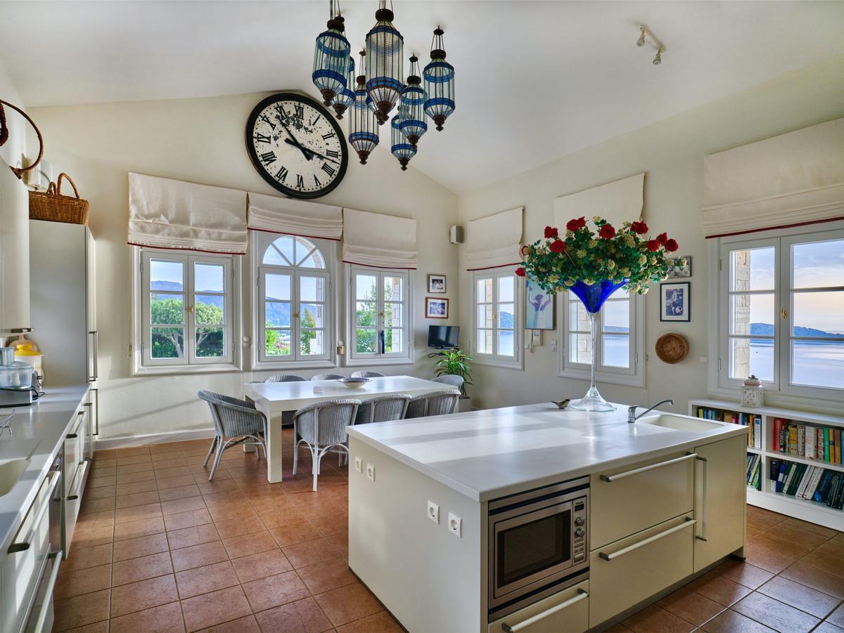 The villa’s gourmet kitchen is equipped with modern appliances, amazing views, and a cozy informal family dining space. (Courtesy of Greece Sotheby's International Realty)