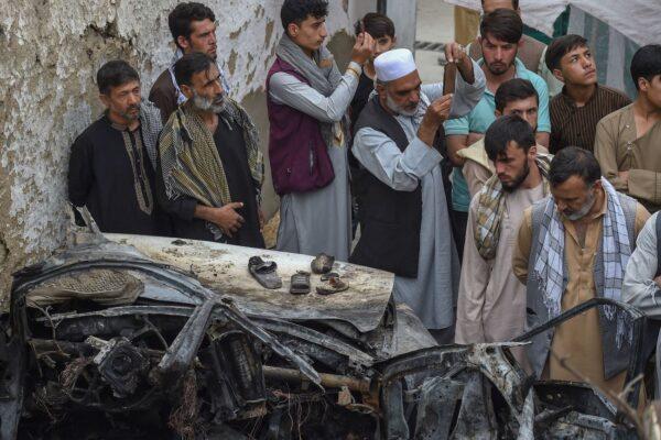Afghan residents and family members of the victims gather next to a damaged vehicle inside a house, day after a US drone airstrike in Kabul on Aug. 30, 2021. (Wakil Kohsar/AFP via Getty Images)