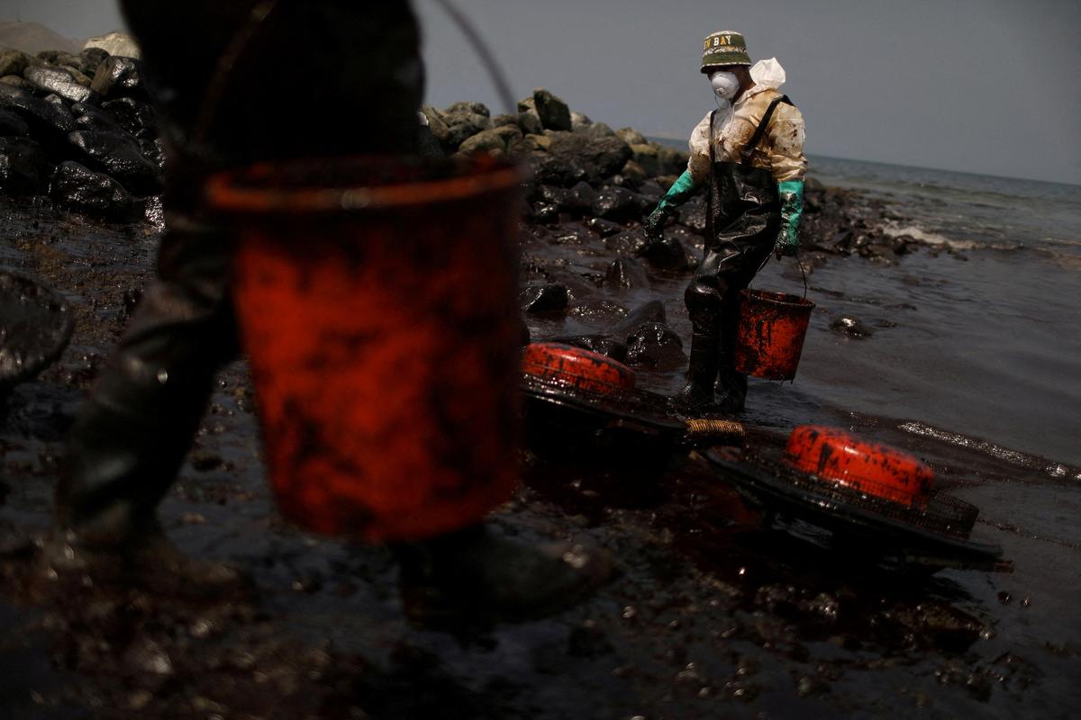Workers clean up an oil spill following an underwater volcanic eruption in Tonga, in Ancon, Peru, on Jan. 25, 2022. (Pilar Olivares/Reuters)
