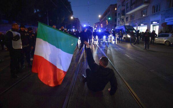 A protester holding the Italian flag sits before anti-riot policemen during a demonstration against the new restrictions imposed by the so-called "super green pass," near Piazza San Giovanni in Rome on Jan. 15, 2022. (Filippo Monteforte/AFP via Getty Images)