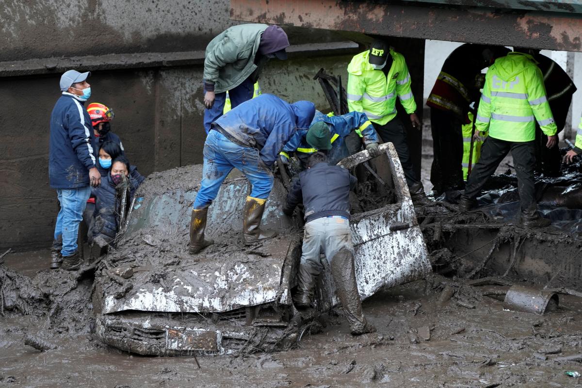 Residents and rescue workers search for people inside a car after a rain-weakened hillside collapsed and brought waves of mud over La Gasca area of Quito, Ecuador, on Feb. 1, 2022. (Dolores Ochoa/AP Photo)
