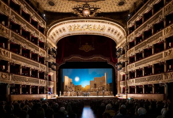 The lights fade, all is dark, the curtain rises and the show begins. The light from the stage gently illuminates the proscenium and the gold-leaf decoration around the theater. (Luciano Romano/Teatro di San Carlo)