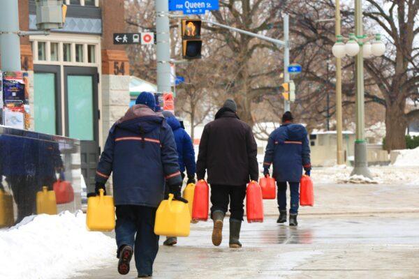 Protesters carry fuel containers in Ottawa as demonstrations against COVID-19 mandates and restrictions continue, on Feb. 9, 2022. (Jonathan Ren/The Epoch Times)