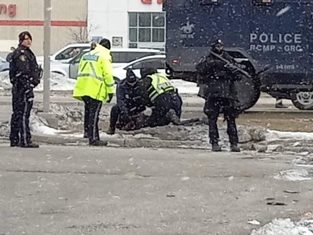 Police make an arrest at the Ambassador Bridge in Windsor, Ontario, while trying to clear a blockade at the Canada-U.S. border crossing, on Feb. 13, 2022. (Lisa Lin/The Epoch Times)