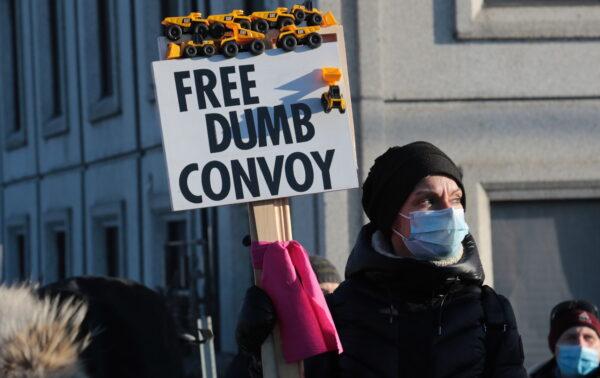 A counterprotester against truckers' protest holds a sign during a demonstration in Ottawa on Feb. 13, 2022. (Richard Moore/The Epoch Times)