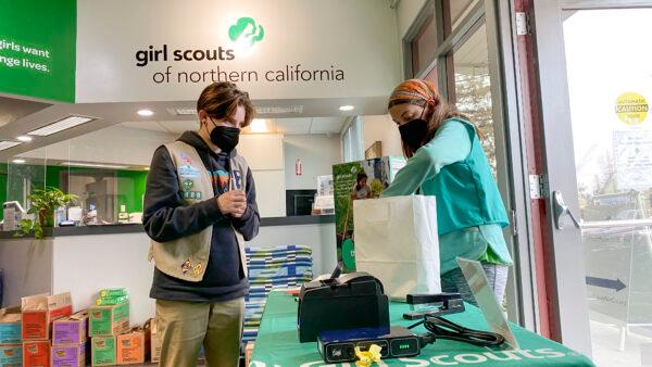 Girl Scouts Arrow (L) and Mariam (R) prepare a DoorDash cookie order for a customer at the Girl Scouts of Northern California San Jose Office on Feb. 14, 2022. (Ilene Eng/The Epoch Times)