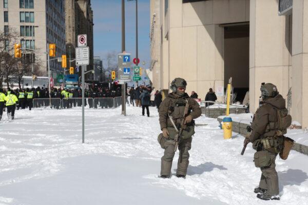 Armed police outside the Westin Hotel in Ottawa on Feb. 18, 2022. To the rear the protest heats up leading to many arrests. (Richard Moore/The Epoch Times)