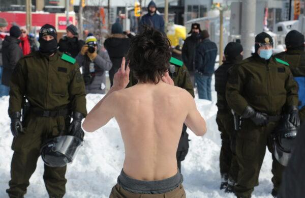 A shirtless man dances in front of police in Ottawa on Feb. 18, 2022. (Richard Moore/The Epoch Times)