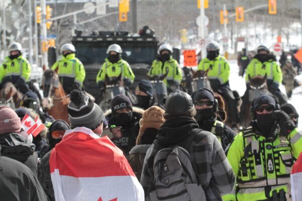 Protesters confront a police line backed up by mounted officers in Ottawa on Feb. 18, 2022. (Richard Moore/The Epoch Times)