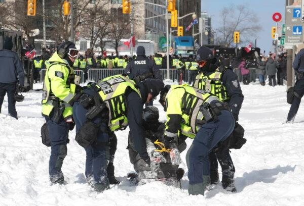 Officers drag a man away from the protest in Ottawa on Feb. 18, 2022. (Richard Moore/The Epoch Times)