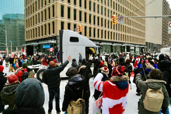 A truck leaves as protesters wave in Ottawa as police continue operations to clear demonstrators on Feb. 18, 2022. (Jonathan Ren/The Epoch Times)