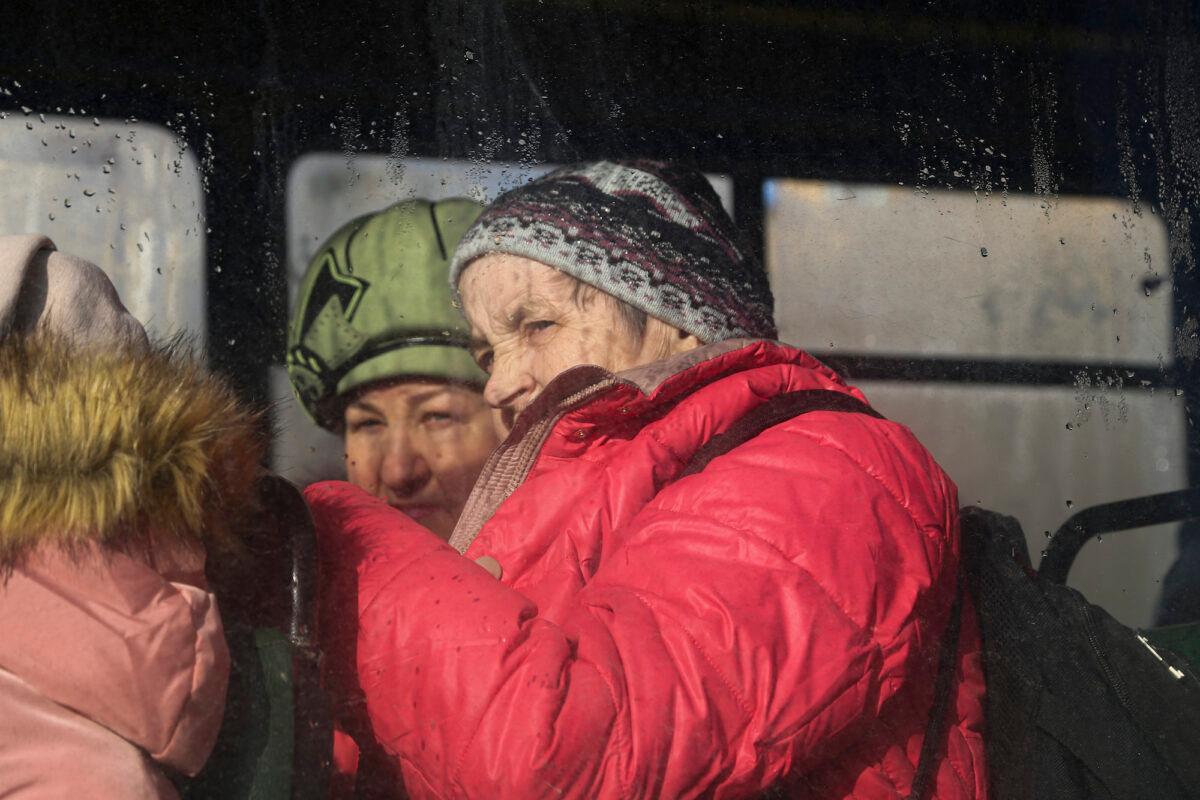 Two women are seen through a bus window, waiting to be evacuated to Russia, in Donetsk, the territory controlled by pro-Russian militants, eastern Ukraine, on Feb. 19, 2022. (Alexei Alexandrov/AP Photo)