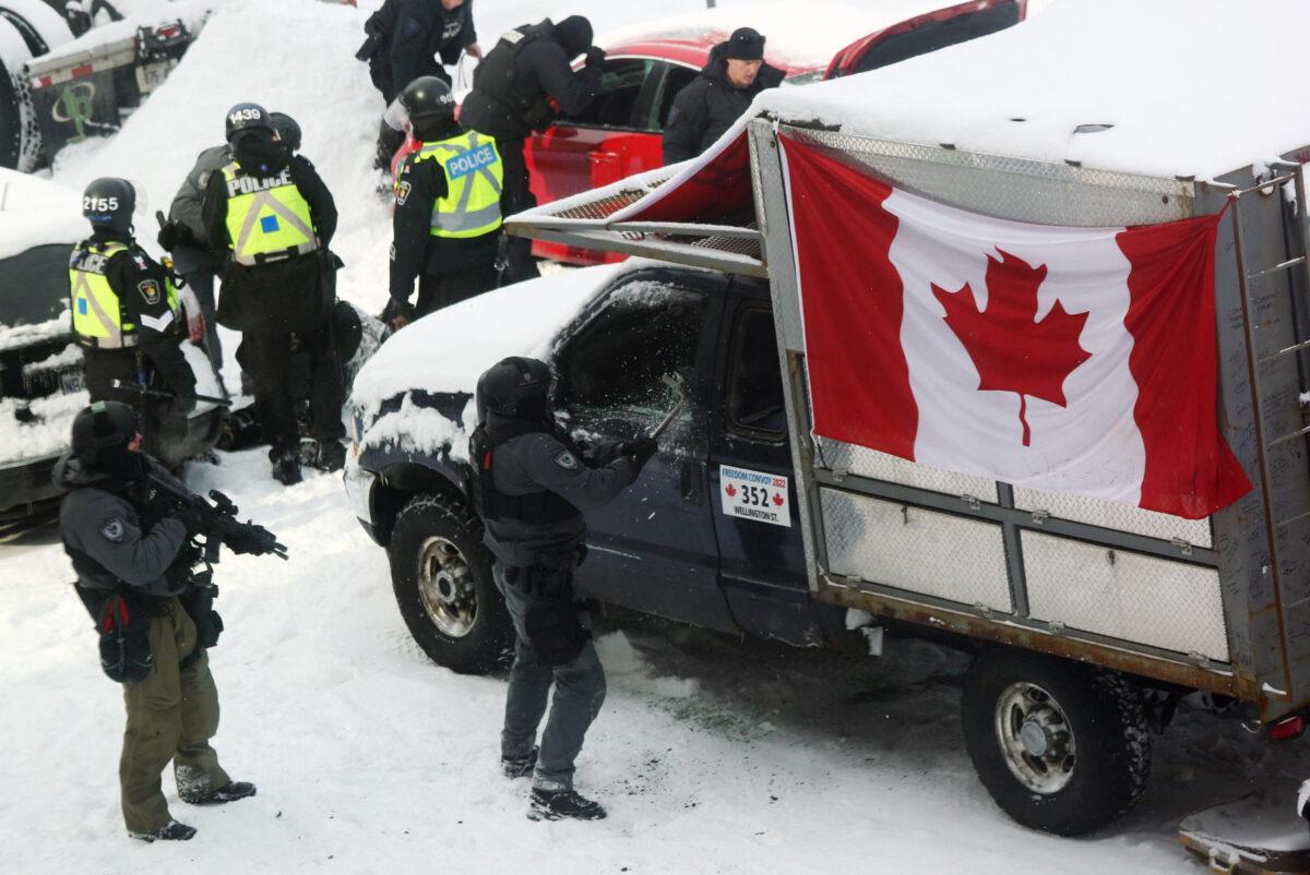 A police officer smashes a truck window as police deploy to remove protesters from downtown Ottawa on Feb. 19, 2022. (Dave Chan/AFP via Getty Images)