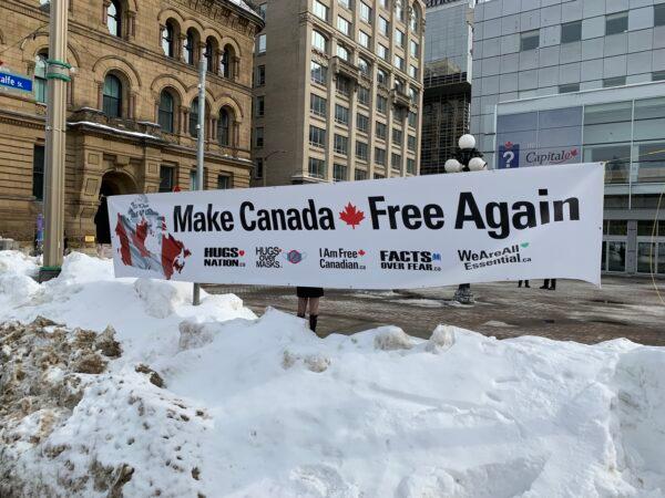 Demonstrators hold a sign in Ottawa by Parliament Hill on March 5, 2022.  (Jonathan Ren/The Epoch Times)