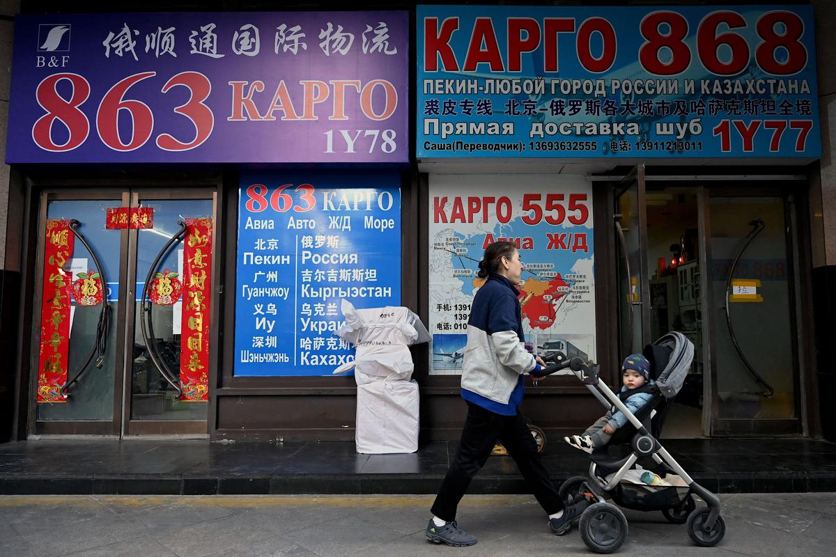 People walk past shopfronts with signage in Cyrillic script at a trading center known as the Russia Market in Beijing on March 3, 2022. (Noel Celis/AFP via Getty Images)