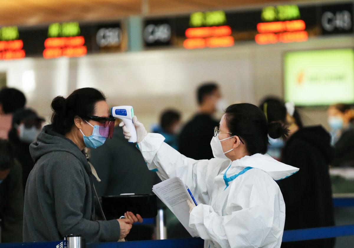 A traveler has a temperature check before checking in for a China Airlines flight at the Tom Bradley International Terminal at Los Angeles International Airport (LAX) amid a COVID-19 surge in Southern California on Dec. 22, 2020. (Mario Tama/Getty Images)