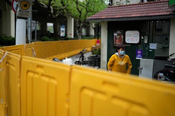 A resident behind barriers sealing off an area under lockdown in Shanghai on April 14, 2022. (Aly Song/Reuters)