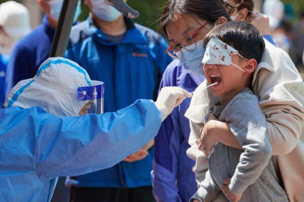 A child receives a swab test for COVID-19 in a compound during a lockdown in Pudong district in Shanghai, China on April 17, 2022. (Liu Jin/AFP via Getty Images)