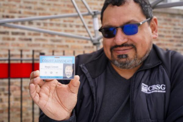Hugo Limon holds his court advocate card while sitting in the community garden on his block on April 11, 2022. (Cara Ding/The Epoch Times)