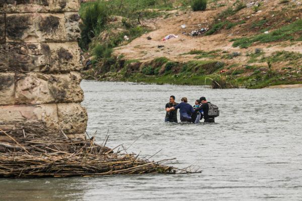 A group of Cubans wade across the Rio Grande from Mexico toward the United States in Eagle Pass, Texas, on April 19, 2022. (Charlotte Cuthbertson/The Epoch Times)