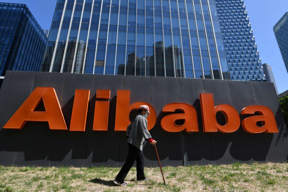 A woman walks past an Alibaba sign outside the company's office in Beijing on April 13, 2021. (Greg Baker/AFP via Getty Images)
