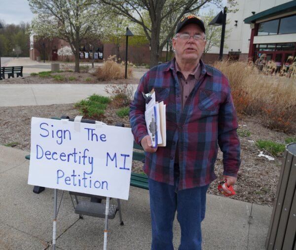 Standing outside the theater that showed D'Souza's film, retired teacher Dan Landon circulates a petition to decertify the results of the 2020 election.  (Steven Kovac/The Epoch Times)