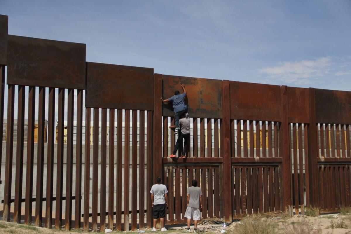A young Mexican helps a compatriot to climb the metal wall that divides the border between Mexico and the United States to cross illegally to Sunland Park, from Ciudad Juarez, Chihuahua state, Mexico on April 6, 2018. (Herika Martinez/AFP via Getty Images)