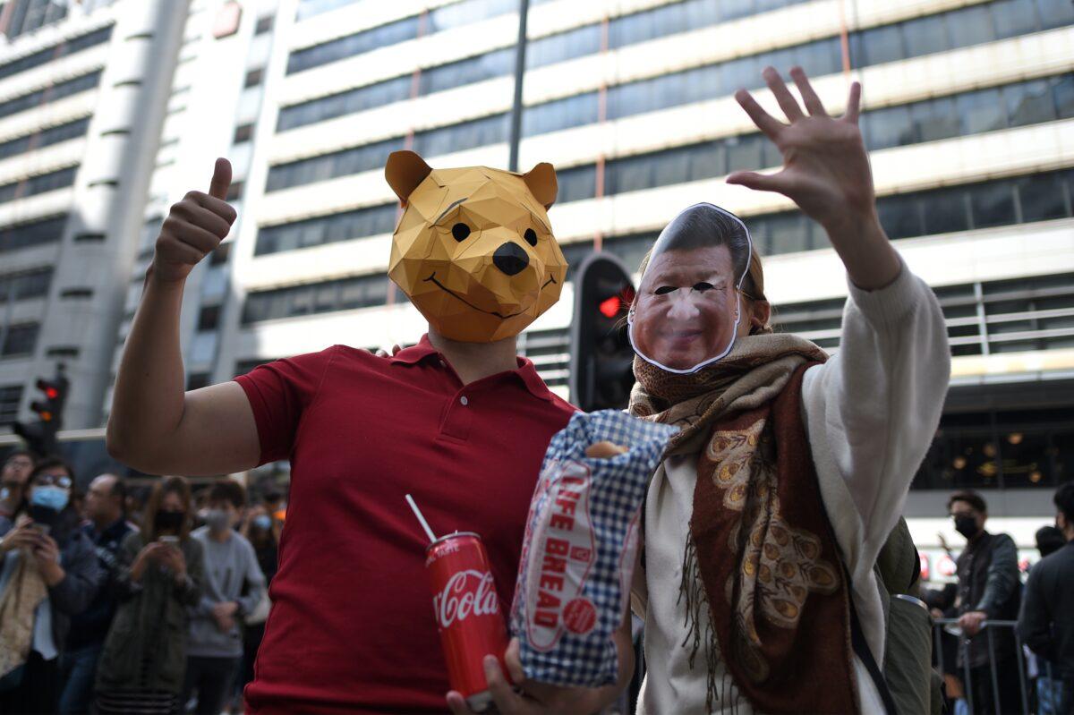 A protester wearing a Winnie the Pooh mask and one wearing a mask of Chinese leader Xi Jinping take part in a mass rally in the Cheung Sha Wan district in Hong Kong on Nov. 29, 2019. (Philip Fong/AFP via Getty Images)