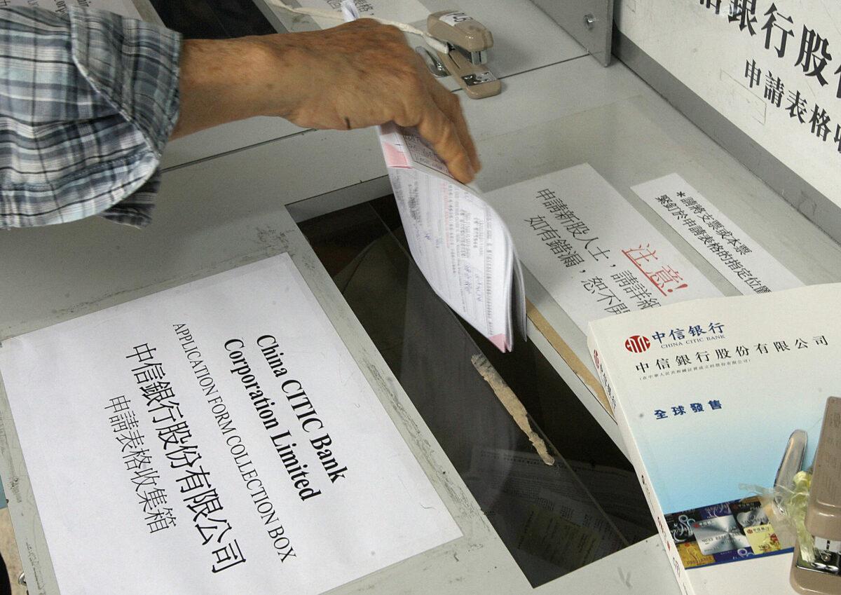 A man places an application form in a box minutes before the deadline ended for the initial public offering (IPO) of China CITIC Bank Corporation Limited in Hong Kong, 19 April 2007. (Mike Clarke/AFP via Getty Images)