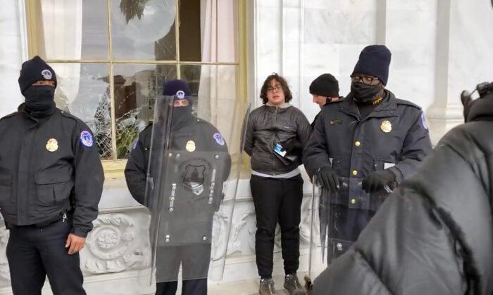 Hunter Ehmke, 21, is detained by police after smashing windows at the U.S. Capitol on Jan. 6, 2021. (Bobby Powell/Screenshot via The Epoch Times)