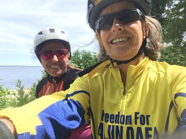 Nearly 70-year-old Mitchell (right), cycles with new friend Ayelet Russo (left) as part of their triathlon training. Mitchell wears the words "Freedom for Falun Dafa" as a way to raise awareness of the mistreatment of people in China who do the same meditation practice she does: Falun Dafa. Persecuted by the communist party, Falun Dafa consists of five sets of exercises and three principles: truthfulness, compassion, and tolerance. (Jeanne Mitchell )