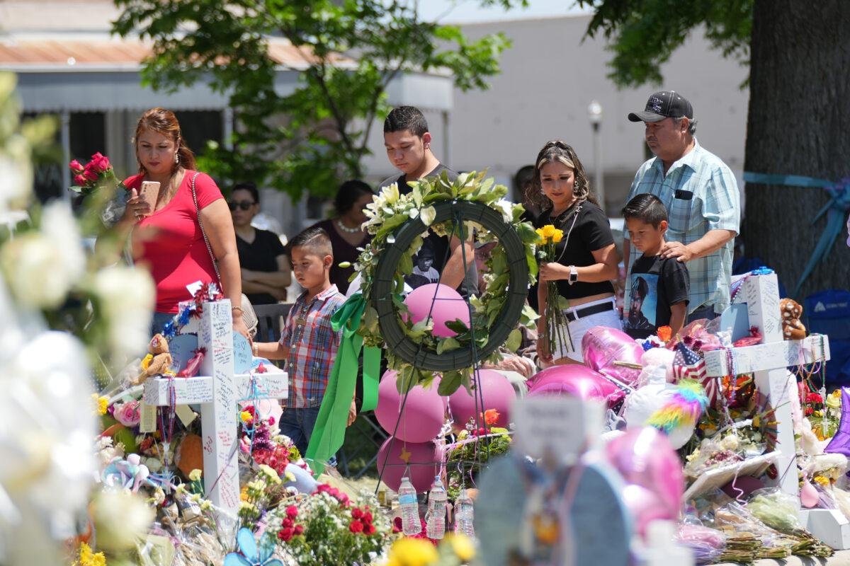 People visit a makeshift memorial for the 21 victims of an elementary school mass shooting in the town square in Uvalde, Texas, on May 29, 2022. (Charlotte Cuthbertson/The Epoch Times)