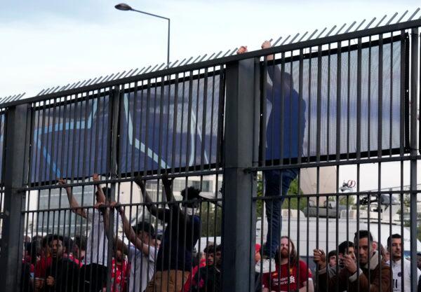 A fan climbs on the fence in front of the Stade de France prior the Champions League final soccer match between Liverpool and Real Madrid, in Saint Denis near Paris, on May 28, 2022. (Christophe Ena/AP Photo)