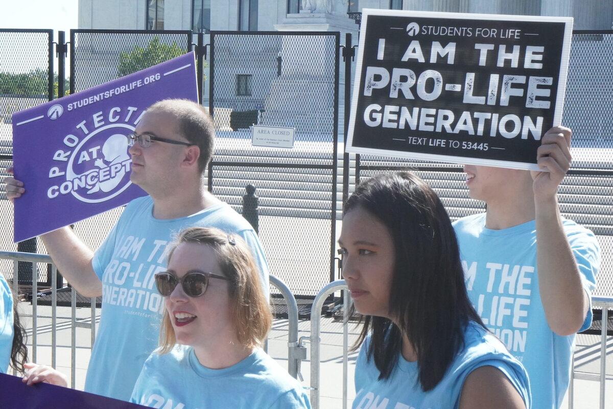 Pro-life protesters with the conservative group, Students for Life, wear blue as they protest outside the U.S. Supreme Court on June 15, 2022. (Jackson Elliott/The Epoch Times)