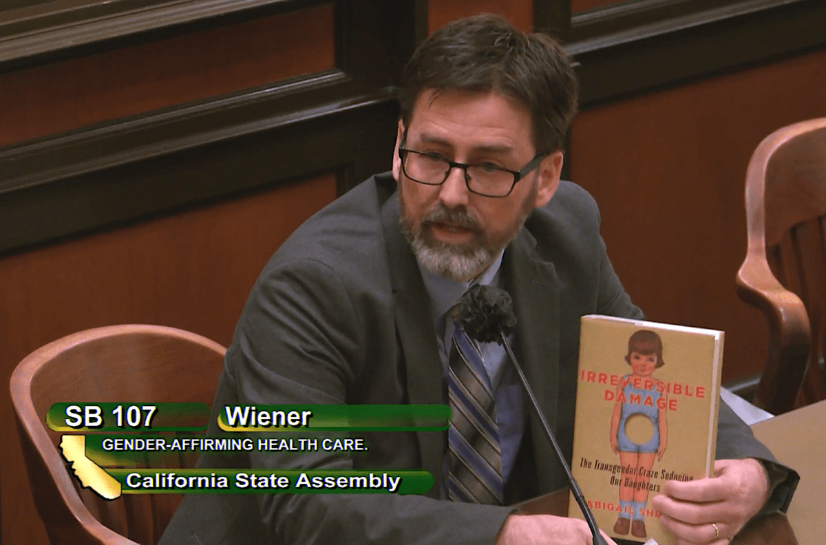 Greg Burt of the California Family Council holds up a copy of Abigail Shrier’s book “Irreversible Damage” at a California Assembly judiciary committee hearing in Sacramento on June 8, 2022. (Screenshot via California State Assembly)
