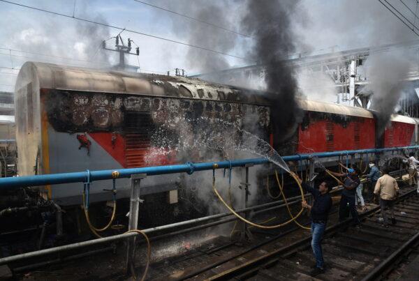 Railway workers try to douse a burning passenger train after it was set on fire by protestors during a protest against "Agnipath scheme" for recruiting personnel for armed forces in Secunderabad in the southern state of Andhra Pradesh, India, on June 17, 2022. (Stringer/Reuters)