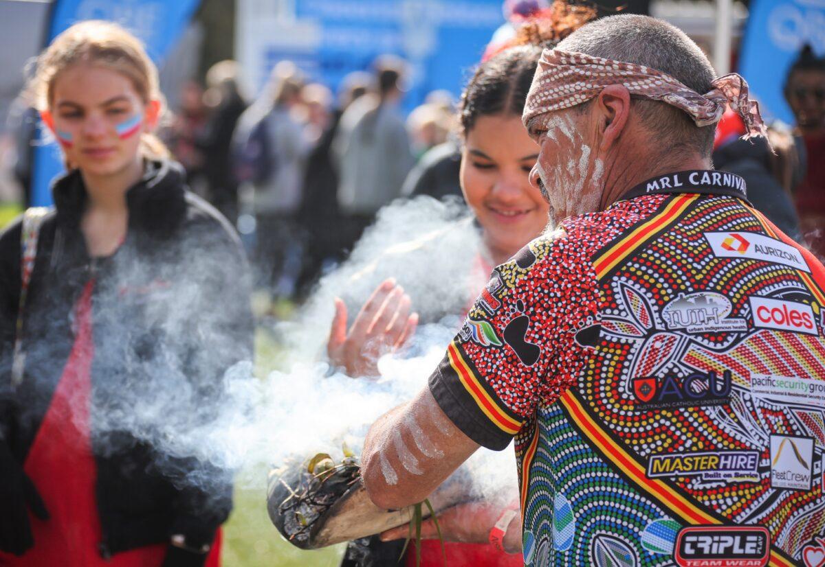An Aboriginal man participates in a smoking ceremony for members of the public before the start of the Super Netball Round 13 match between the NSW Swifts and the West Coast Fever at Ken Rosewall Arena in Sydney, Australia, on June 5, 2022. (AAP Image/David Gray)