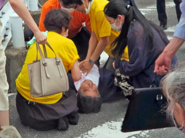 Japan’s former Prime Minister Shinzo Abe, center, falls on the ground in Nara, western Japan, on July 8, 2022. (Kyodo News via AP)