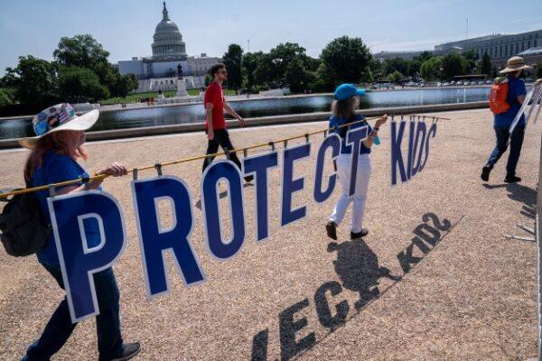 Attendees hold a sign reading protect kids not guns during the Moms Demand Action Gun Violence Rally in Washington on June 8, 2022. (Nathan Howard/Getty Images)