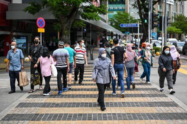 People cross a street in Kuala Lumpur, Malaysia, on Oct. 8, 2021. (Mohd Rasfan/AFP via Getty Images)